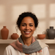 Portrait of a diverse woman with a genuine smile, against a warm cream background.