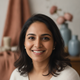 Close-up portrait of a smiling South Asian woman, exuding warmth and trust against a soft, blurred background.